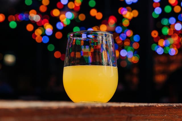 Stemless wine glass containing orange juice-based cocktail