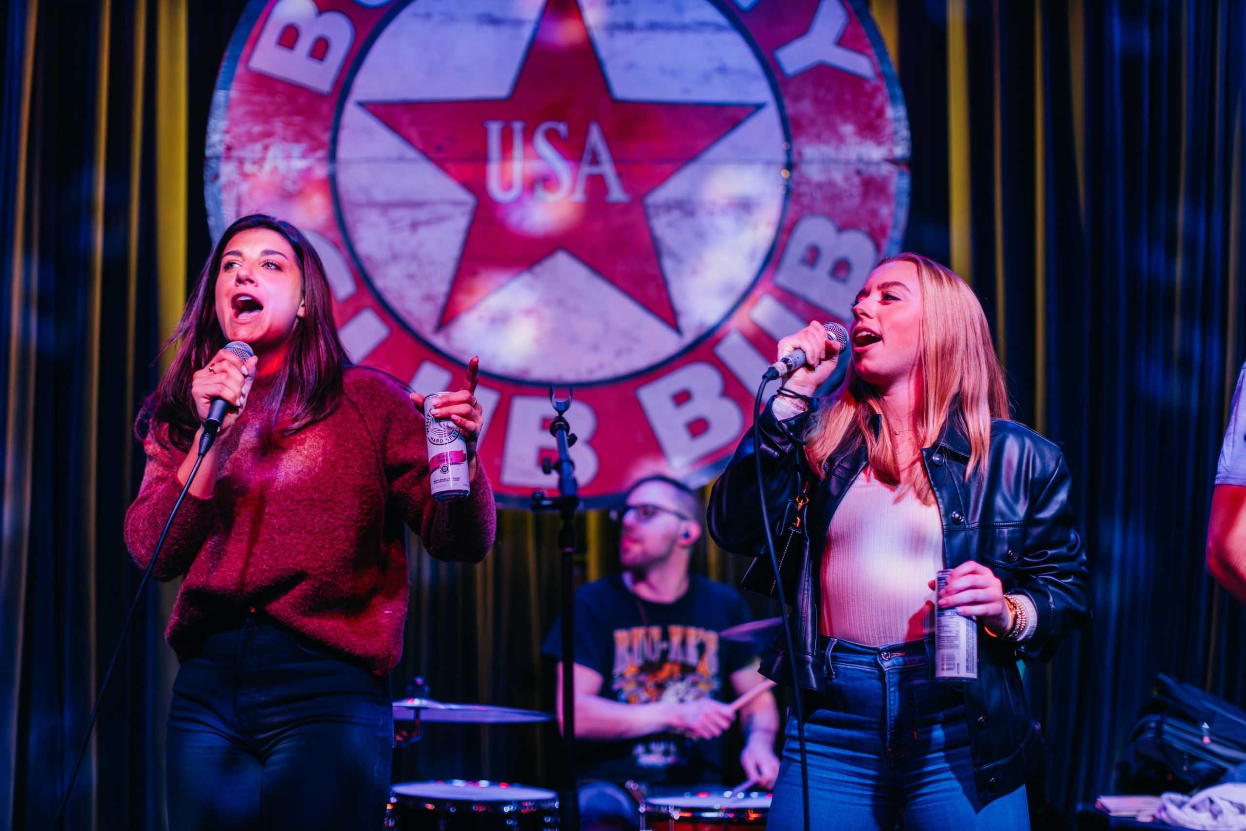 two people singing on stage in front of a drummer