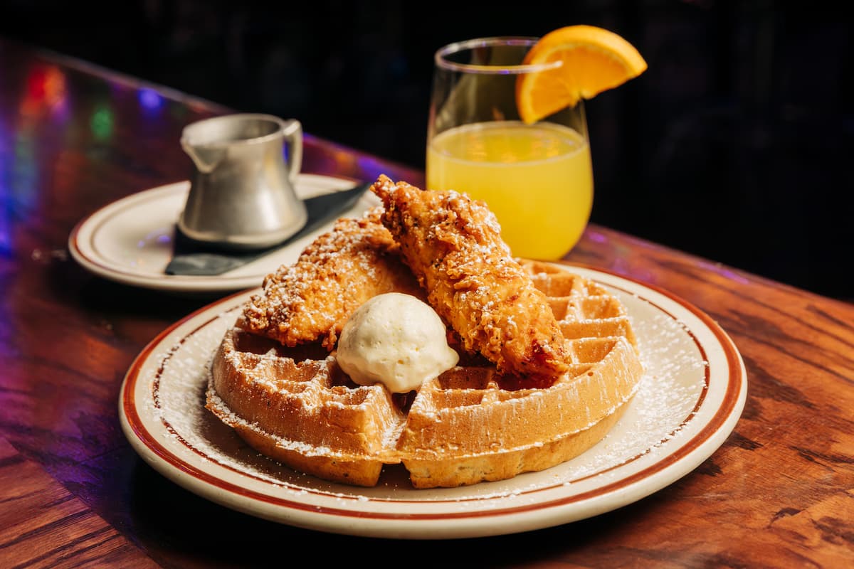 Fried Chicken Waffle on a plate with a mimosa in the background.